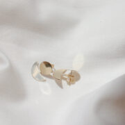 Złote kolczyki księżyce z możliwością regulacji zawieszki na jasnym materiale.