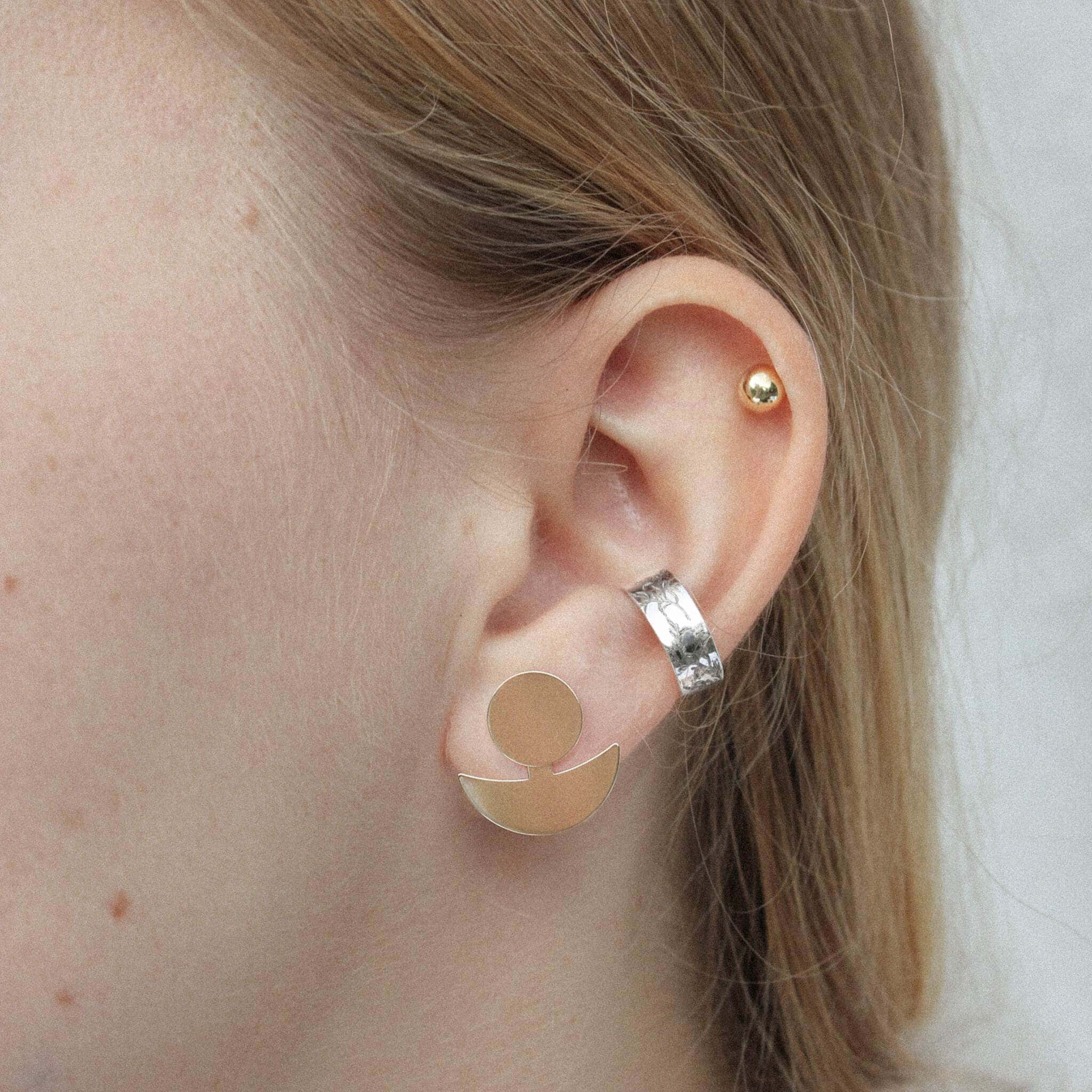 The model is wearing gold earrings in the form of the Moon and earcuff with floral motifs.