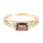 Złoty pierścionek z kwarcem dymnym i diamentami na jasnym tle.