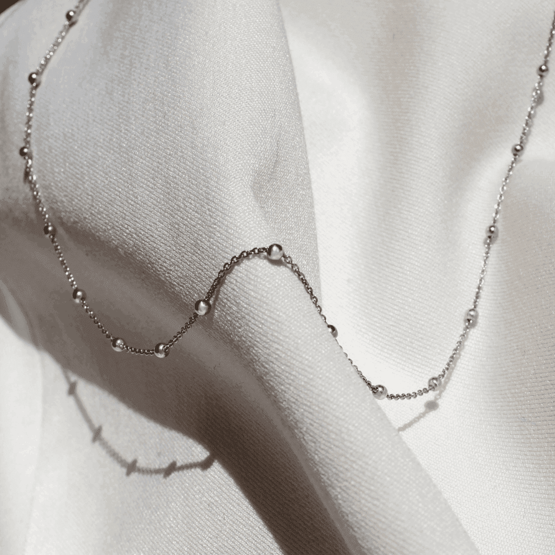 Silver necklace chain PINS on bright material.
