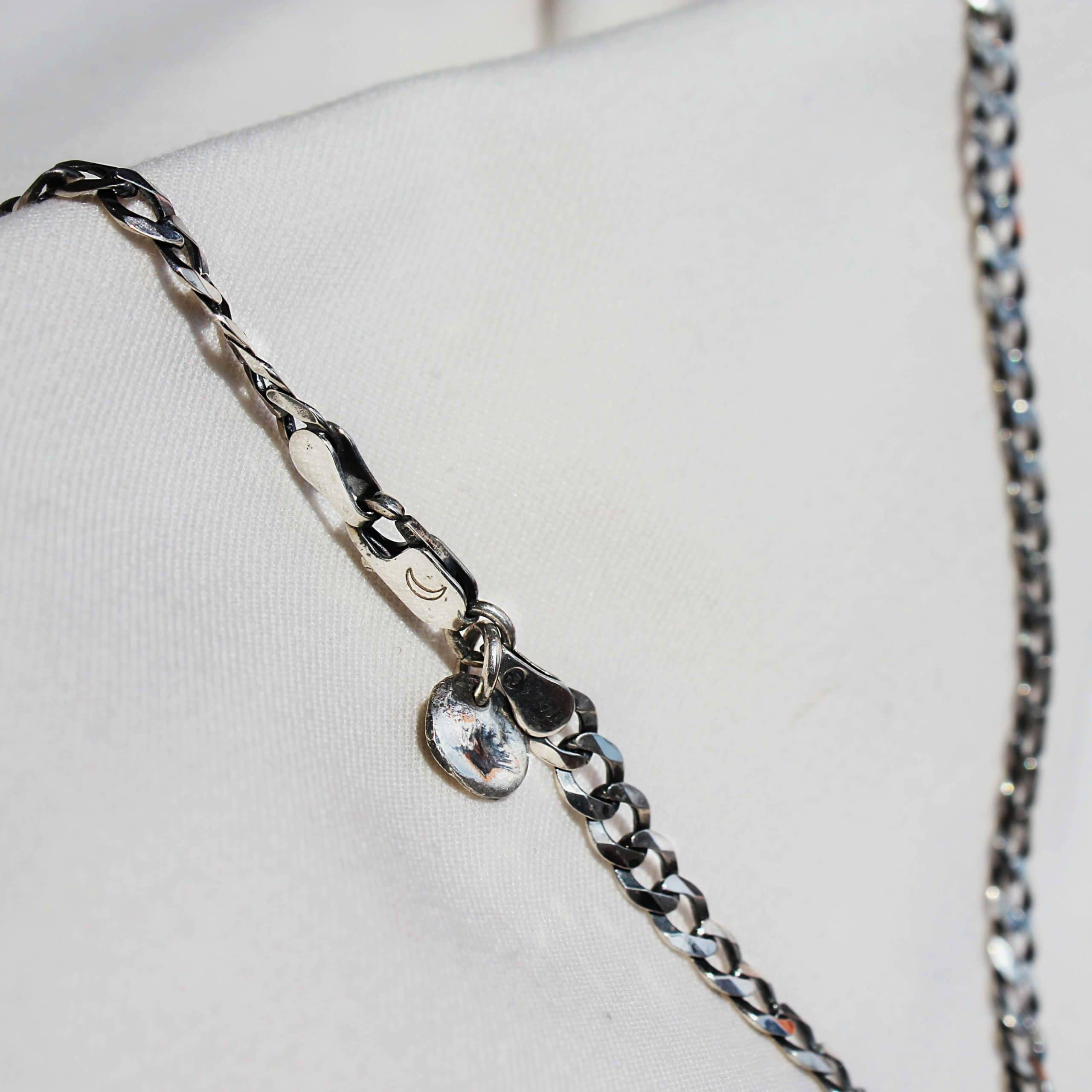 A silver necklace with Moon pendant on whie material