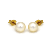 Złote kolczyki z perłą na jasnym tle.