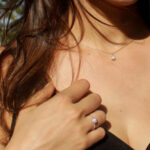 Modelka prezentuje złoty pierścionek zaręczynowy z diamentem.