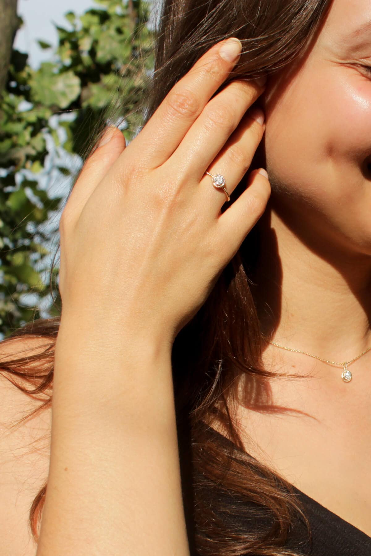 Engagement gold diamonds ring and gold diamond pendant on model.