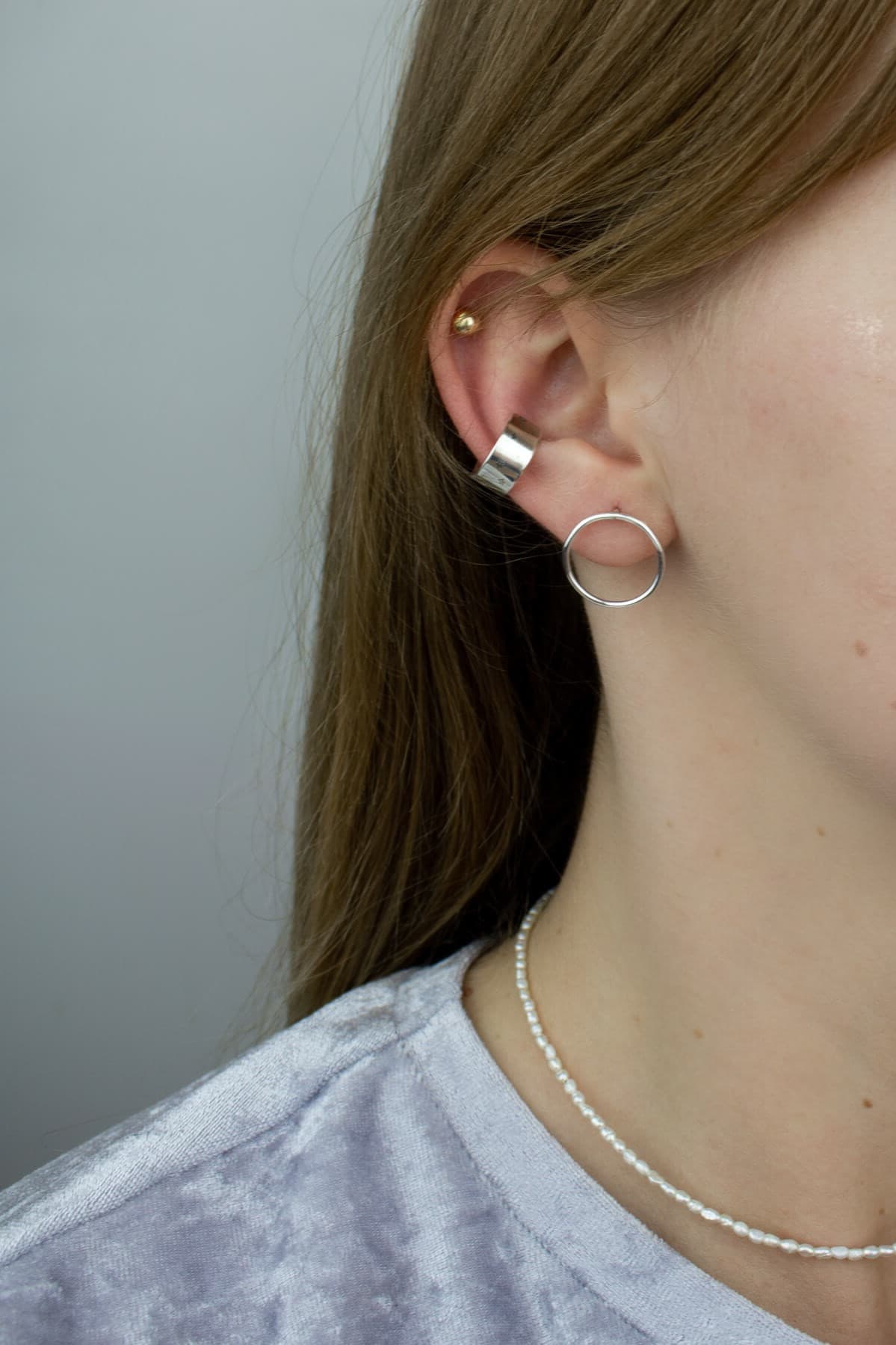 Designer jewelry, silver circle earrings and silver ear cuff on model