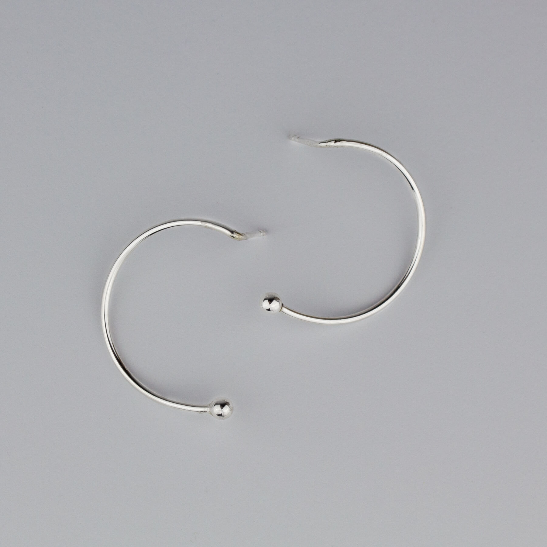 Silver semicircle earrings on white background; view from up.