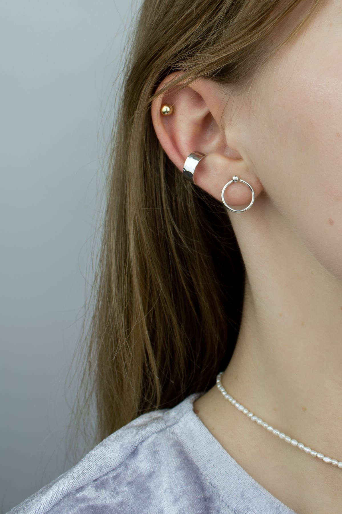 Small circle earrings, a silver ear cuff and a pearl choker on the model