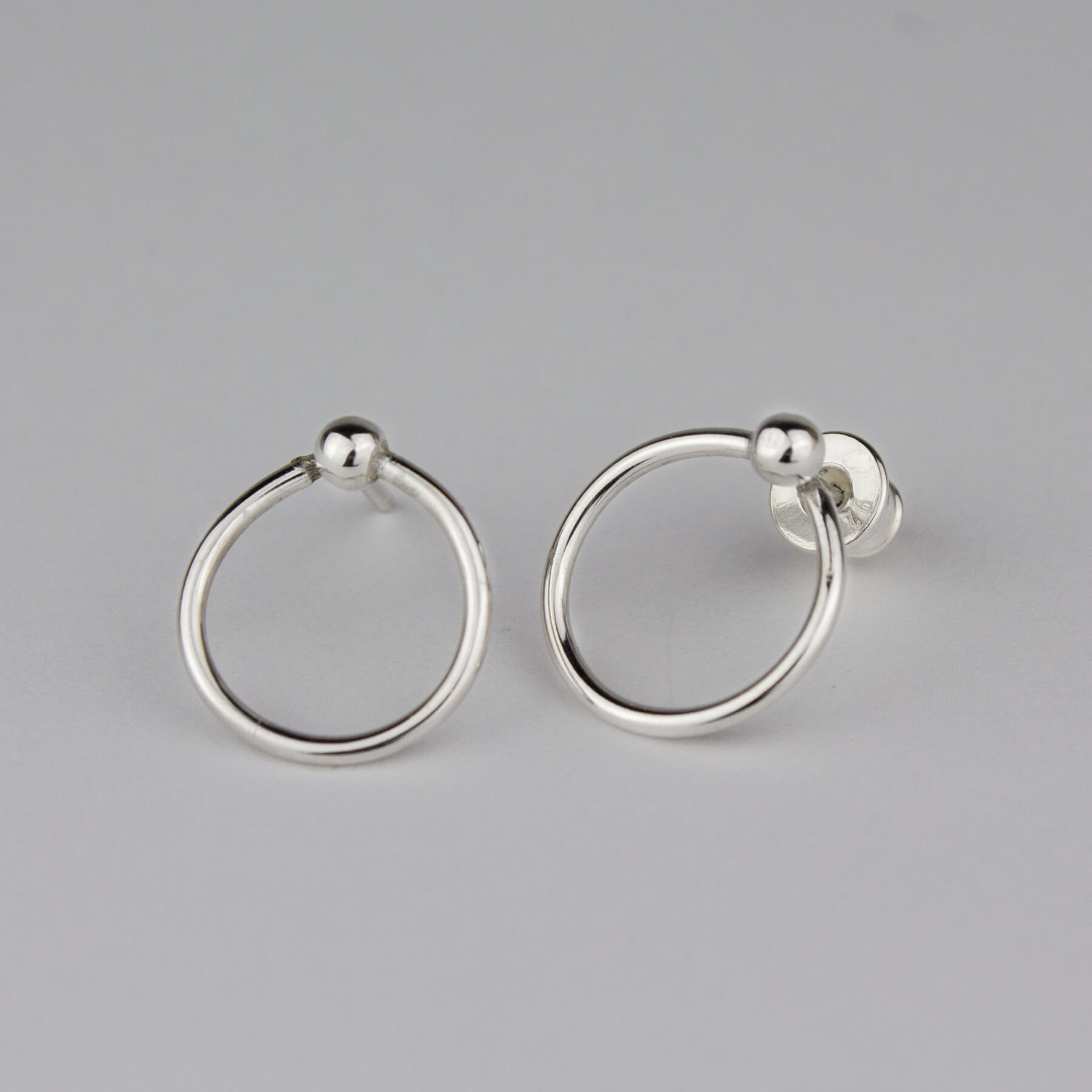 Small silver circle earrings on bright background