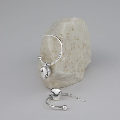 Silver hoop earrings with heart pendant with moon engraving on white stone.