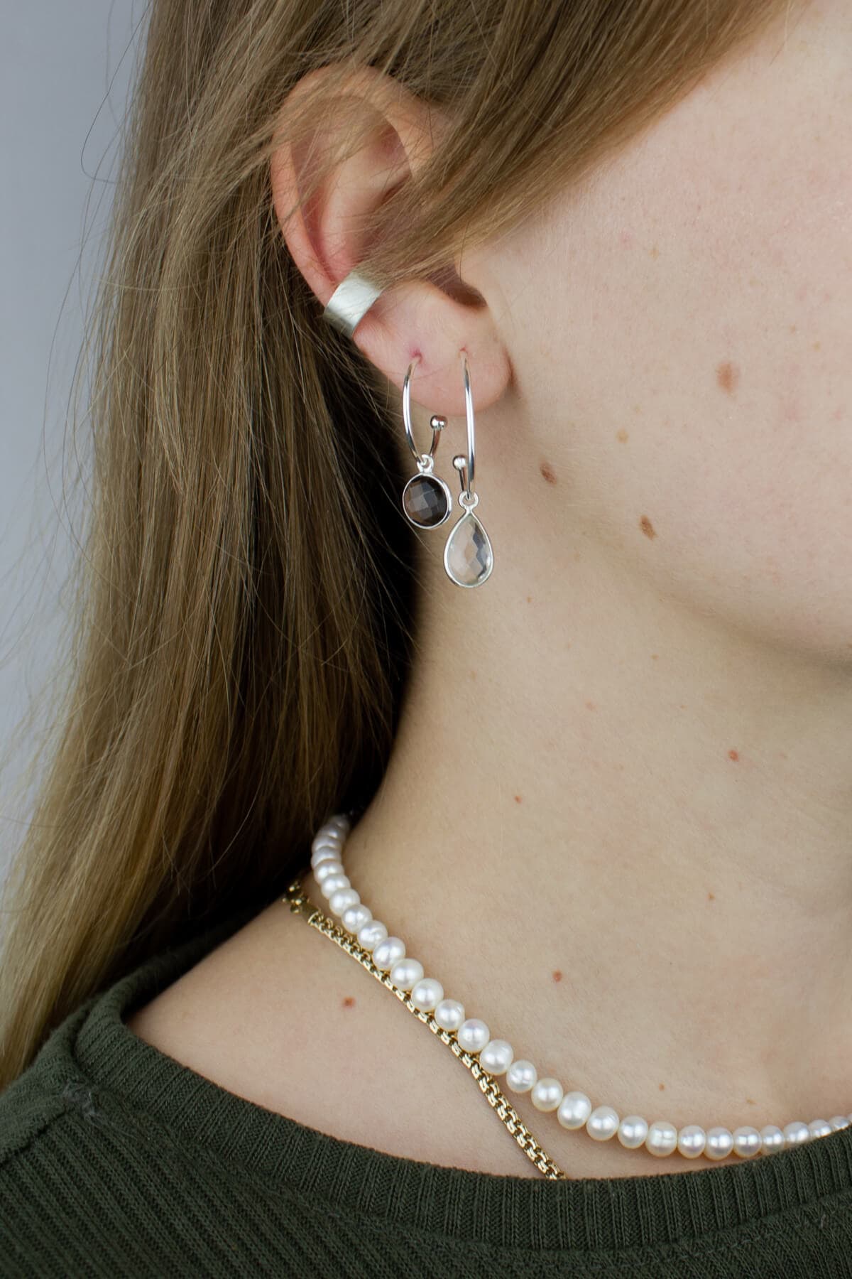 Silver hoop earrings with crystal quartz, silver ear cuff and pearl necklace on a model