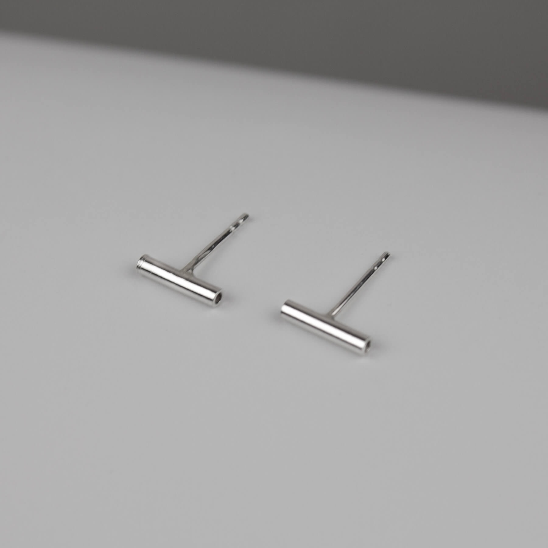 Silver line earrings on a bright background.