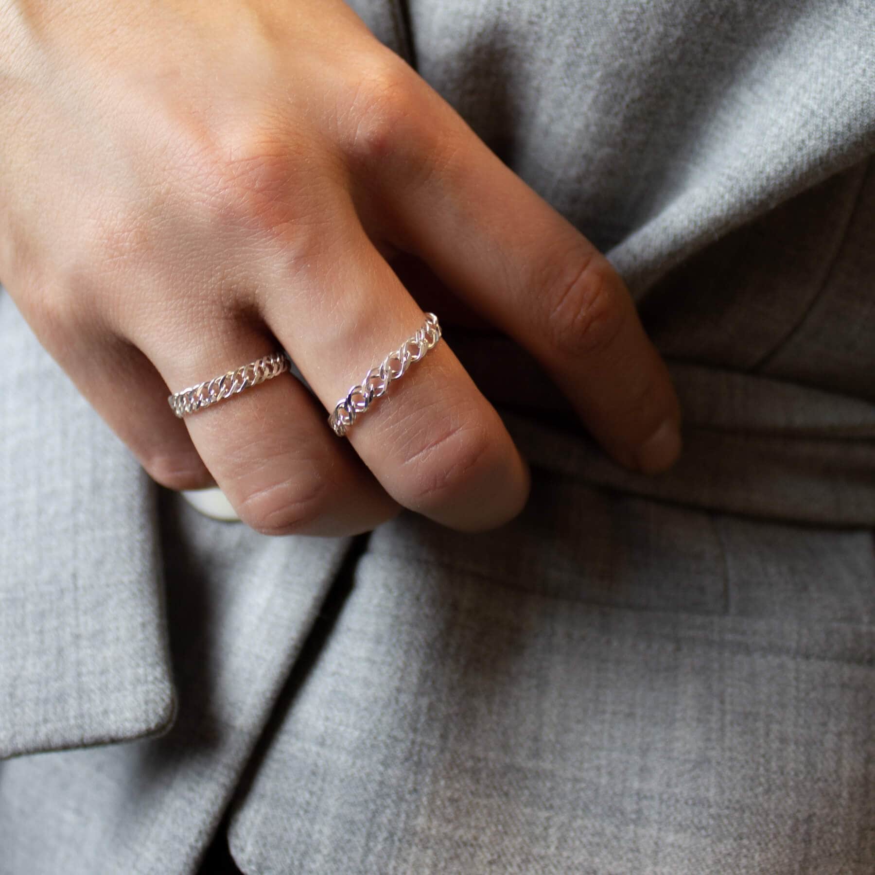 Silver chain rings on the model who is wearing a gray jacket.
