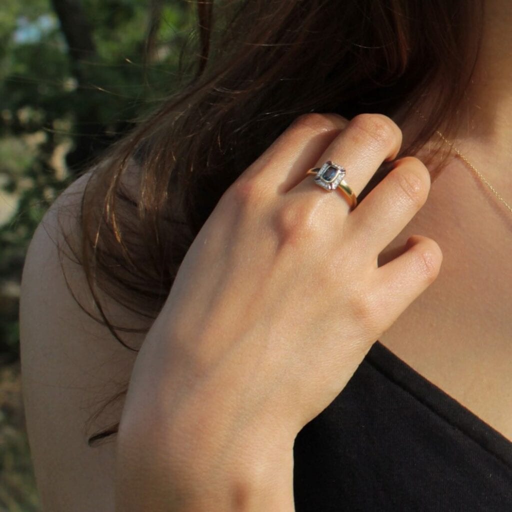 Pierścionek zaręczynowy z topazem i diamentami na modelce, która ubrana jest w czarną sukienkę.