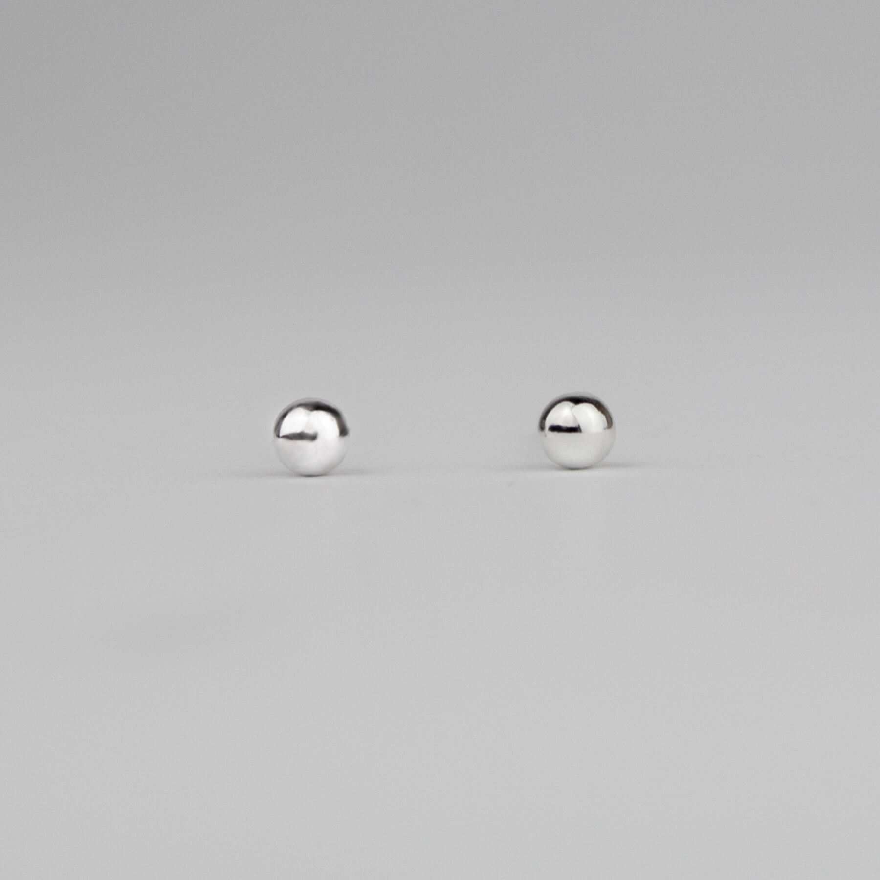 Silver ball earrings on a light background