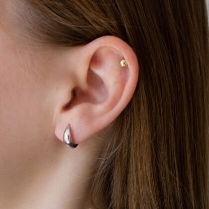 Małe srebrne kolczyki huggie na modelce