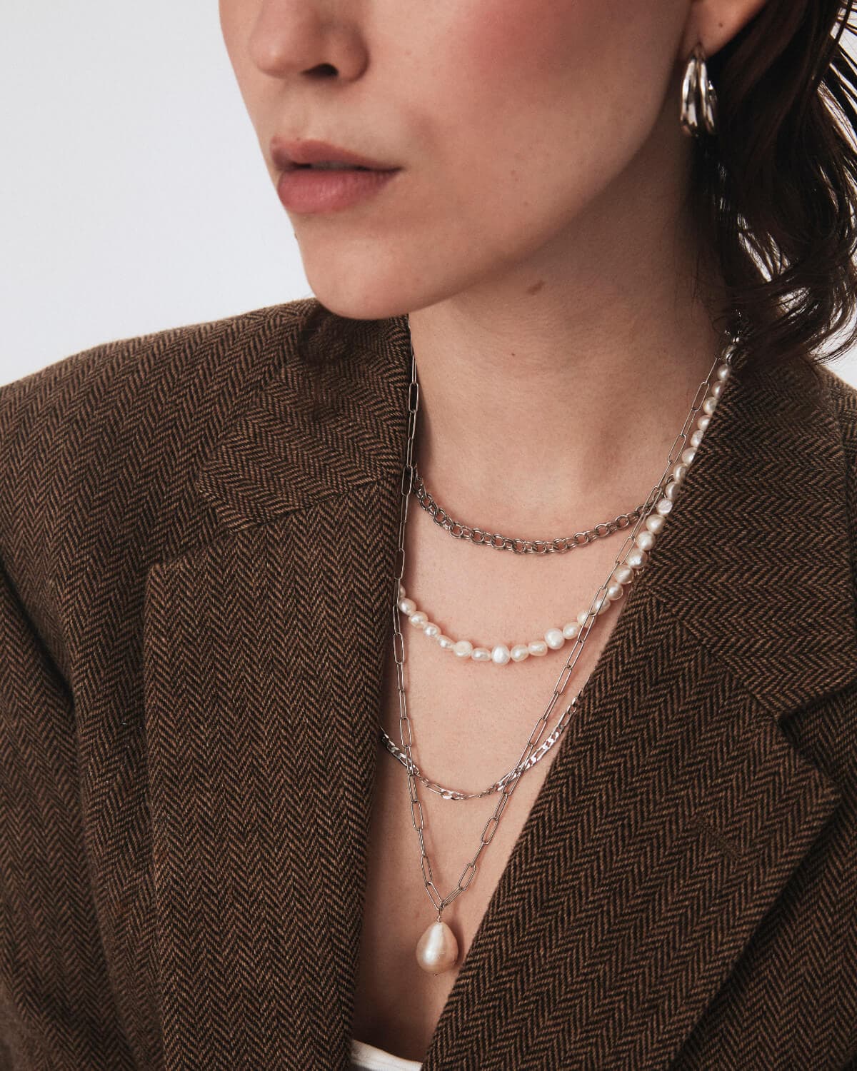 Pearl necklace and silver chains on a model
