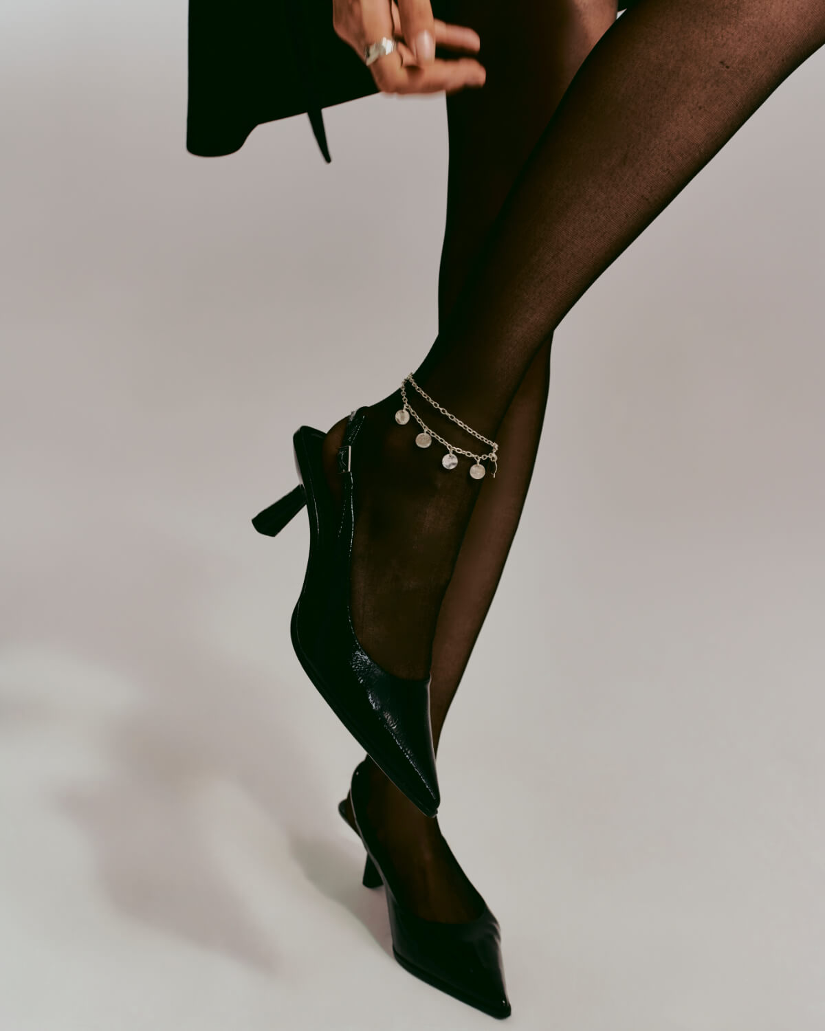 Anklet necklace with charms on a model wearing a black jumpsuit