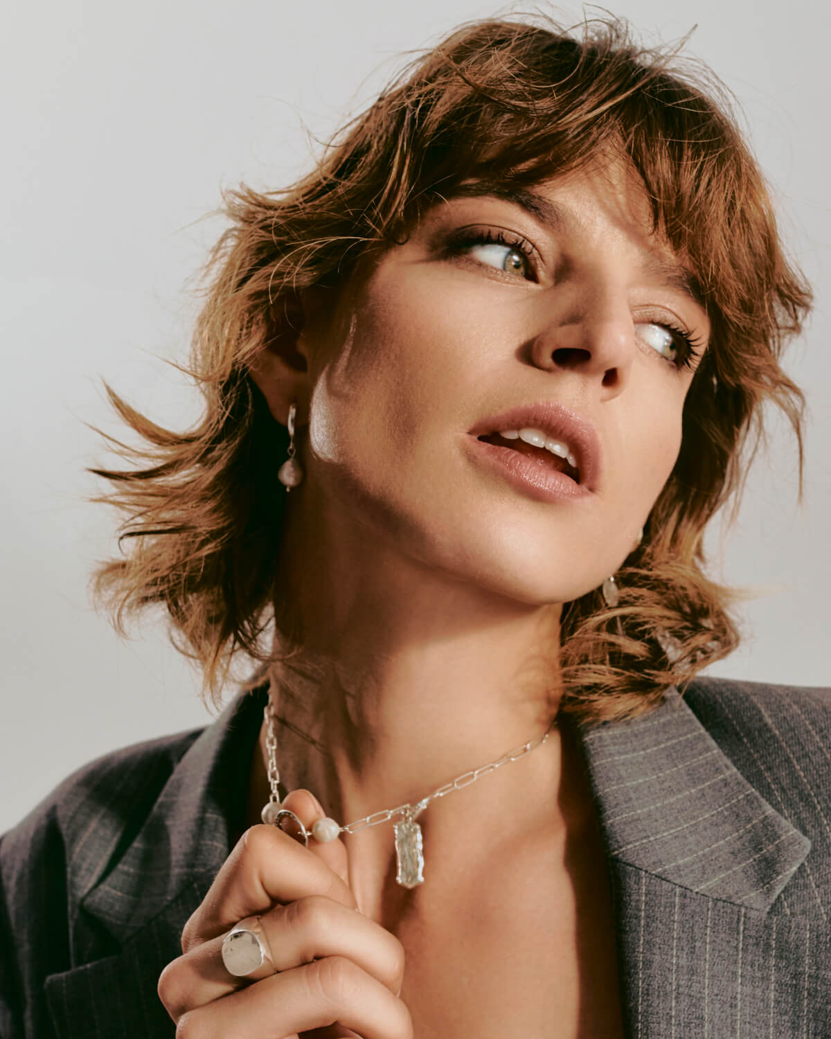 Silver baroque pearl drop earrings and necklace on a model with curly hair