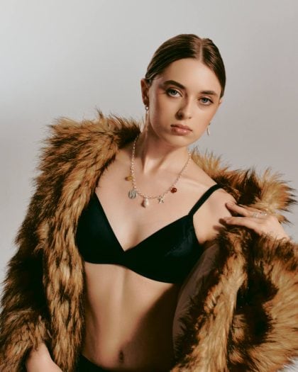 Wiszące kolczyki z zawieszką perłą koła oraz naszyjnik z dużymi zawieszkami na modelce ubranej w futro