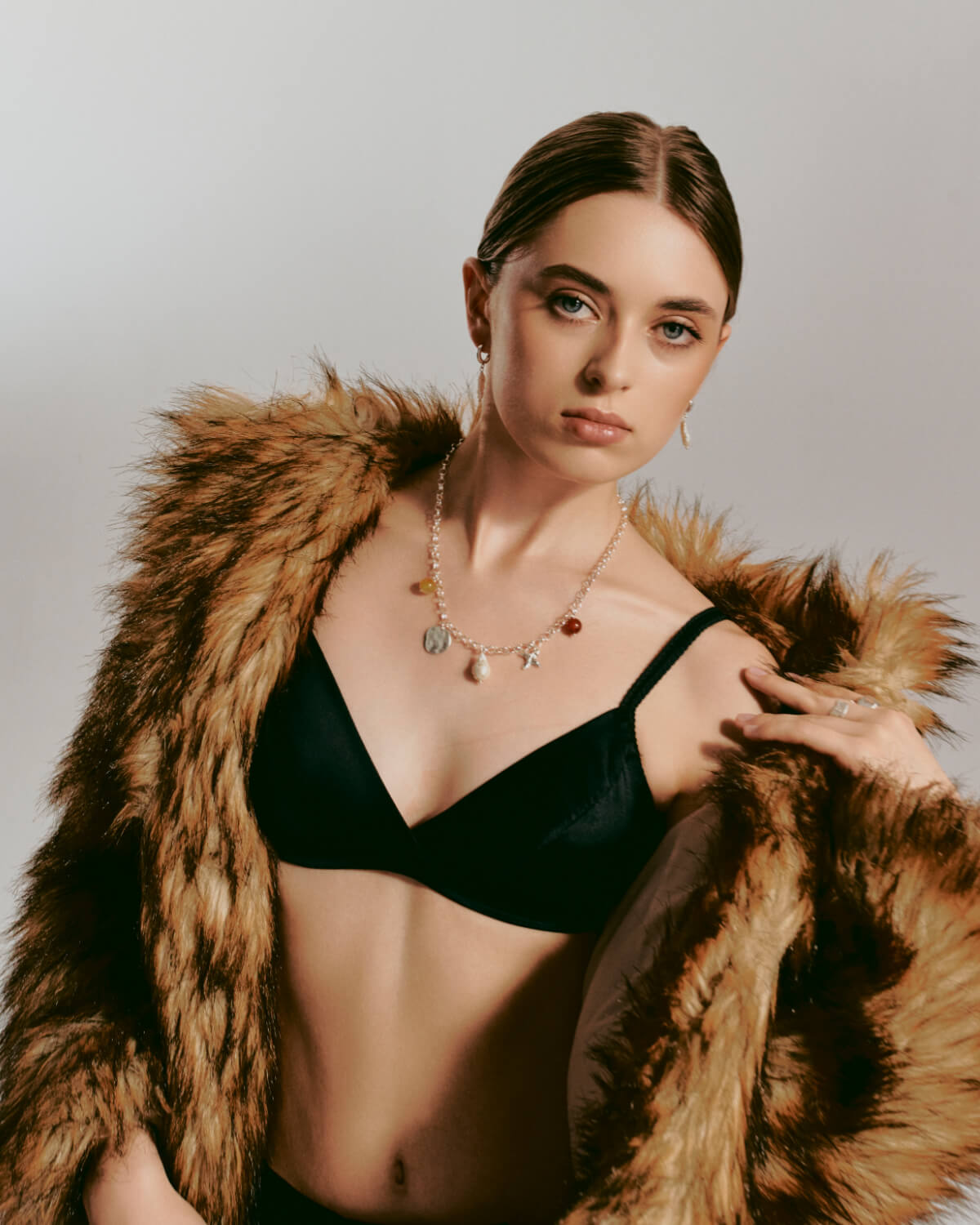 Pearl hoop earrings and a necklace with large pendants on a model wearing a fur coat