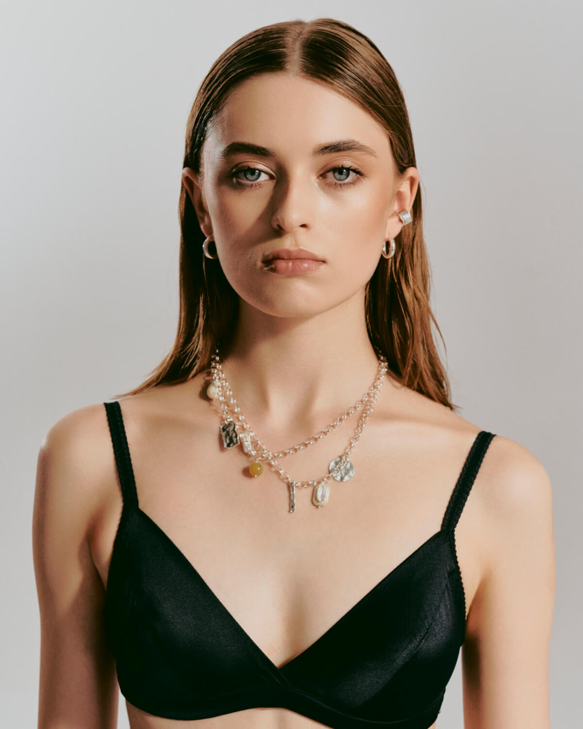 A massive necklace with silver pendants and an ear cuff on a model